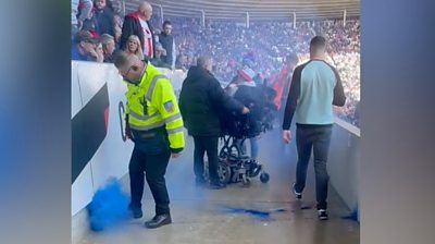 A plume of blue smoke rises into the air after a flare lands in the disabled fans' section at Sunderland's Stadium of Light