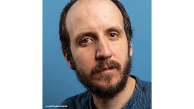 A headshot of writer Jack Thorne, who is wearing a blue and white striped shirt, has brown hair, a moustache and beard and looks directly into the camera. An image credit reads Antonio Olmos.