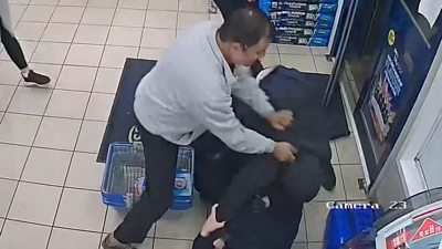A man is seen on CCTV walking towards a door with a crate of beer before being tackled.