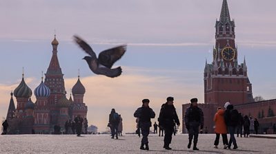 Russian law enforcement walk in red square, with St Basil's Cathedral and the Kremlin visible behind them