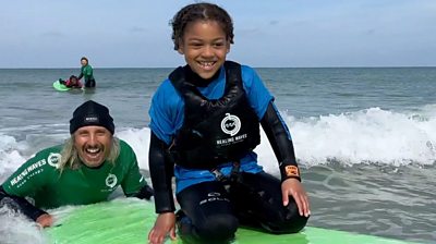 Child on surfboard with instructor