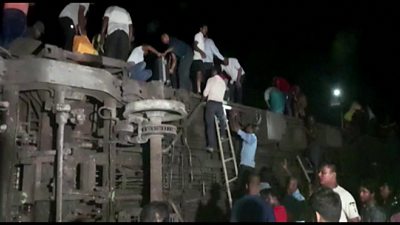People in India climb over a derailed train