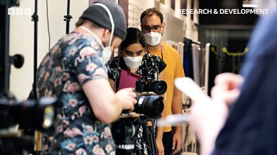 Camera crew using equipment in masks