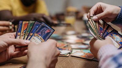 People holding hands of cards on a table