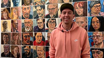 Rod Kitson standing in front of his portraits