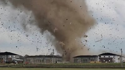 Tornado funnel cloud sends debris into air