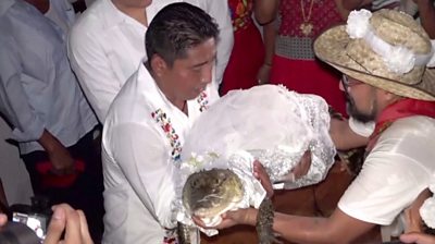 Mayor holding caiman dressed in bridal outfit