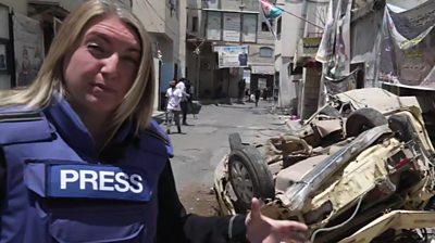 Middle east correspondent Anna Foster, next to an overturned car