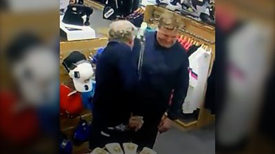Two men on CCTV putting golf clubs down trousers