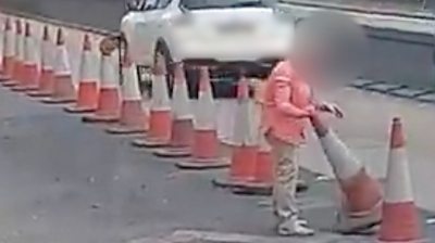 Woman moving a traffic cone on the A12 in Essex