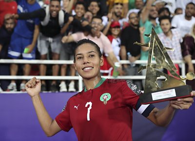 Ghizlane Chebbak in Morocco kit holds up a trophy and poses in front of fans