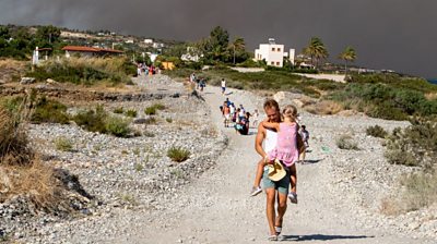 A man carries a child away from smoke