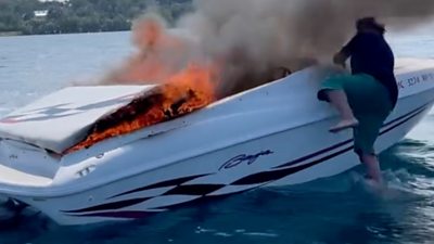 Man jumping from burning boat into water