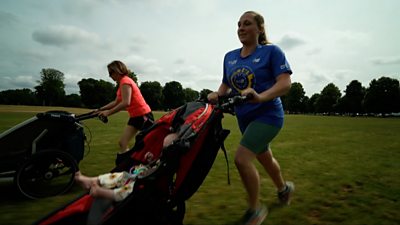 Zoe Jacobs and friend running in a field pushing their babies in prams