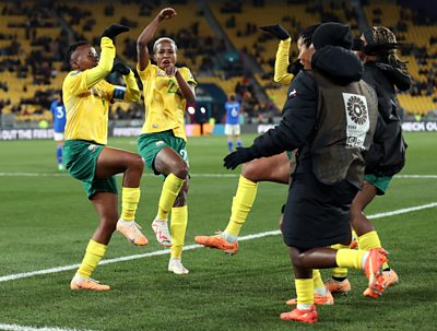 South African players rush to celebrate on the pitch as Thembi Kgatlana strikes a pose after scoring