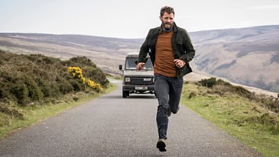 Jamie Dornan runs on a road in a valley