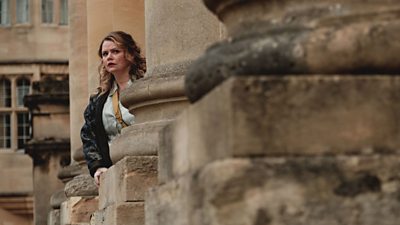 A woman looks concerned on the steps of a country house