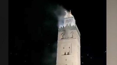 Tall section of mosque smoking at night following earthquake