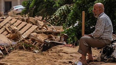 Man sitting down looking at flood devastation