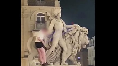 Man climbing lion statue