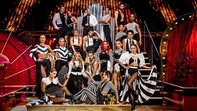 The Strictly Come Dancing 2023 professional dancers pose on a gold platform and stairs, which have been set up on the ballroom floor. They all wear black and white for a special dance, which they perform with the judges.