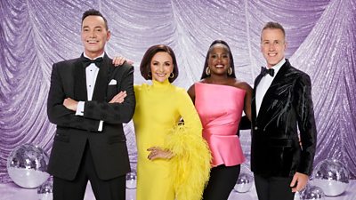 Anton Du Beke and Craig Revel-Horwood in a suit and bowtie, Shirley Ballas in a yellow dress, Motsi Mabuse in a pink top and black trousers.