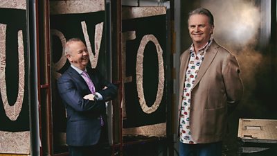 Ian Hislop and Paul Merton backstage at Have I Got News For You. They stand, laughing, behind the set.