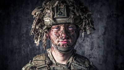 Man in army uniform and camouflage helmet and dirt on face