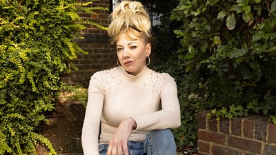 Diane Morgan as character Mandy with blonde hair in a high bun looking to camera
