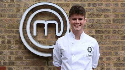 Man wearing chefs clothing smiling in front of MasterChef M