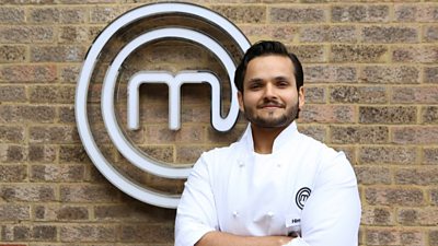 Man wearing chefs clothing smiling in front of MasterChef M