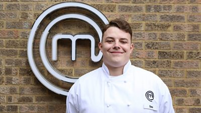 Man wearing chefs clothing smiling in front of MasterChef M