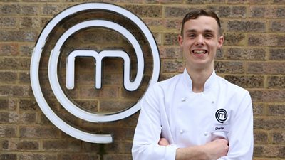 Man wearing chefs clothing smiling in front of MasterChef M