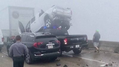 A truck sitting on top of another truck after huge car pile-up incident