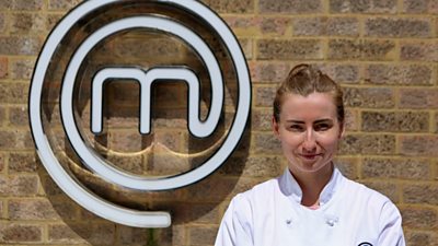 Woman wearing chefs shirt in front of MasterChef M