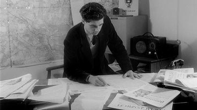 Charles Wheeler is seen looking through the German press in the BBC German service office