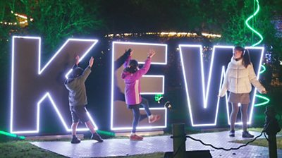 Children dance in front of a Kew Gardens signs