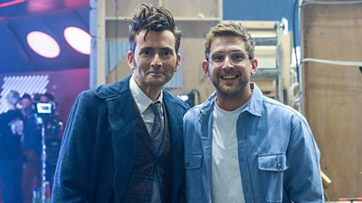 The Doctor (David Tennant) and Steffan Powell stand smiling outside the TARDIS