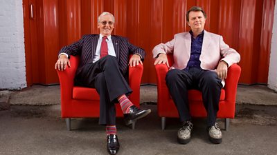 Picture of Nicholas Parsons and Paul Merton sat in red armchairs facing the camera and smiling. 