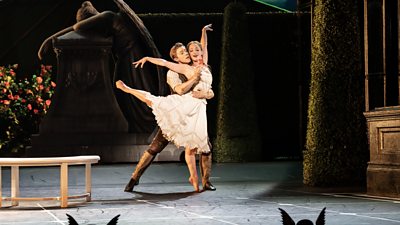 Two ballet dancers on stage in Matthew Bourne's Sleeping Beauty - the man holds a flower, wrapping one arm around the waist of the woman who is dancing in an outdoor garden scene