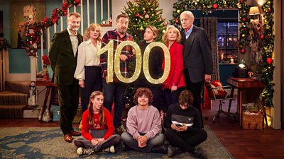 The cast of Not Going Out sit and stand in front of a Christmas tree holding a large glittering number 100. Back row: Toby (Hugh Dennis), Anna (Abigail Cruttenden), Lee (Lee Mack), Lucy (Sally Bretton), Wendy (Deborah Grant), Geoffrey (Geoffrey Whitehead) Front Row: Molly (Francesca Newman), Benji (Max Pattison), Charlie (Finley Southby)