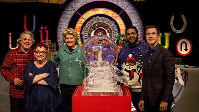 Alan Davies, Jo Brand, Sandi Toksvig, Eshaan Akbar and Jimmy Carr in the QI studio, standing around a giant block of ice, shaped like a magnifying glass, with a letter i at the centre