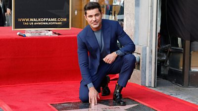 Zac Efron touching his star the Hollywood Walk of Fame