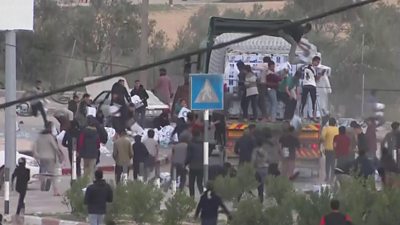 Men on the back of an aid lorry throw boxes down onto crowds below