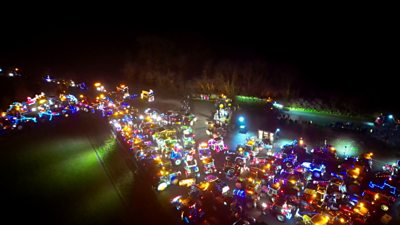hundreds of tractors light up like christmas trees on a field