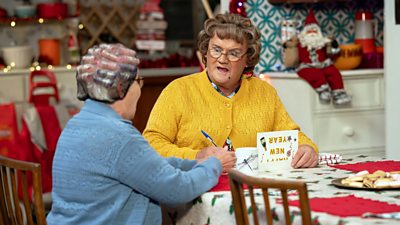 Winnie (Eilish O'Carroll) and Agnes Brown (Brendan O'Carroll) sit at the kitchen table