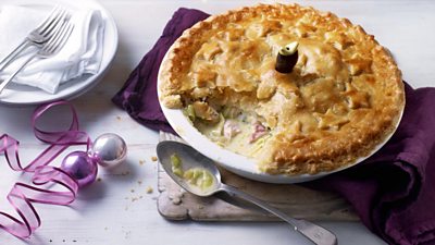 A pie in a dish, dotted with pastry stars. One slice has been cut out and some of the filling is visible.