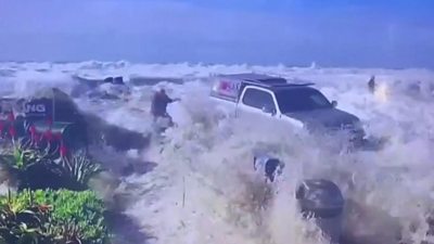Waves crash into people and vehicles