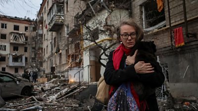 A local resident holding a cat leaves the site where residential buildings were heavily damaged during a Russian missile attack