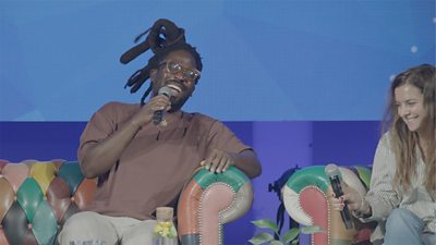 A man speaks into a microphone at a panel